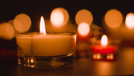 Close-Up-Of-Romantic-Lit-Red-And-White-Candles-Burning-On-Black-Background-With-Bokeh-Lighting